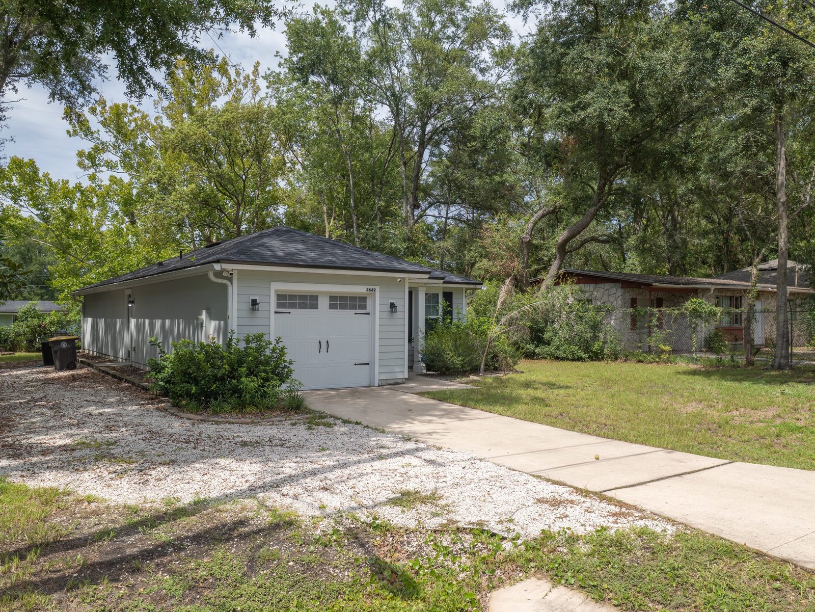 4649 Suray Avenue — Front Angle with Gravel Parking Area Beside the Garage